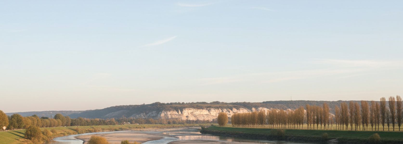 The middle Loire seen from a low earth flood bank, wide shallow water broken by pale sandbars, poplars along the far bank.